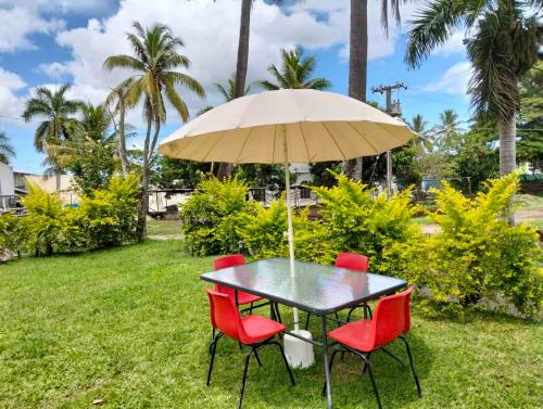 a black table with red chairs and an umbrella at Navo Apartment Homes in Nadi
