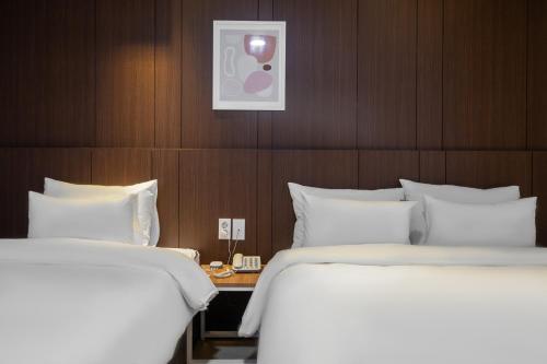 two beds in a hotel room with white sheets at Sasang ND 1226 Hotel in Busan