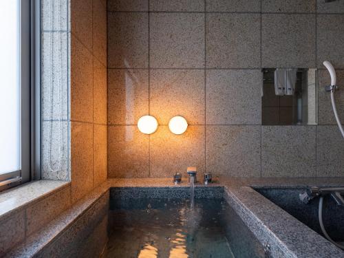 ein Badezimmer mit Badewanne und Waschbecken in der Unterkunft 小樽旅亭 蔵群 in Otaru