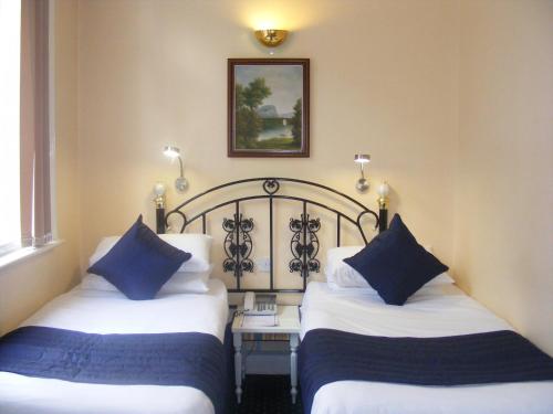 2 Betten in einem Hotelzimmer mit blauen Kissen in der Unterkunft Mermaid Suite Hotel in London