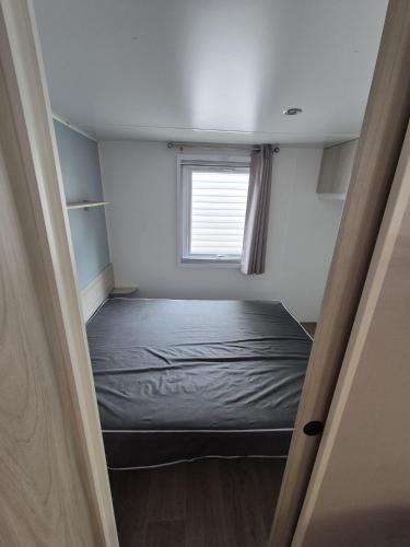 a small room with a bed and a window at Vias plage "MER & SOLEIL" Mobil home camping La Carabasse 6 a 8 personnes in Vias