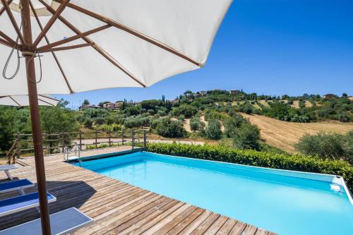 a swimming pool with an umbrella next to a wooden deck at La Fontaccia 13 by VacaVilla in Montiano