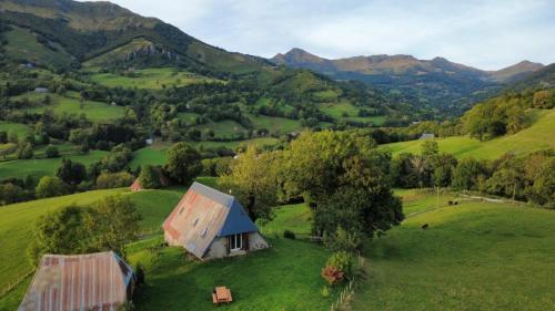 een oude schuur op een groene heuvel met bergen op de achtergrond bij Le Pradima in Mandailles