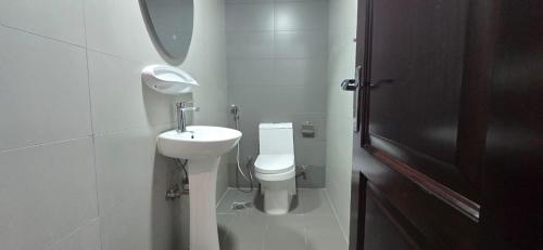 a white bathroom with a toilet and a sink at Peaceful Apartments in Dubai