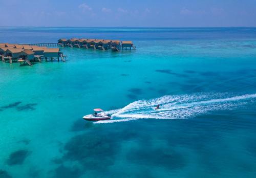 a boat in the water next to a resort at Centara Ras Fushi Resort & Spa Maldives - 50 percent discount on transfers for min 4 nights stay and more, valid for reservations between 11th Feb till 22 Dec 2025 in North Male Atoll