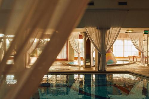 a swimming pool in a room with curtains at Egri Korona Borház és Wellness Hotel in Demjén