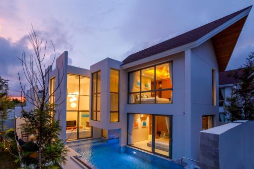 a house with a swimming pool at dusk at Elite Living - Design 3BR Pool Villa in Newly Built LuxPride 4 L6 Residence in Bang Tao Beach