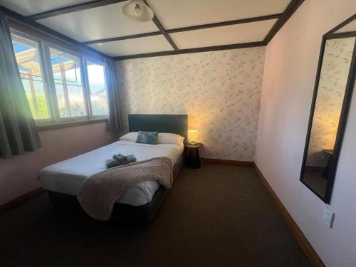 Un dormitorio con una cama en una habitación con ventana. en Chic 4 bedroom City Home with large Garden, en Palmerston North