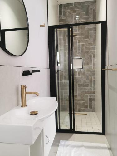 a bathroom with a shower with a sink and a mirror at Going places BnB in Queenstown