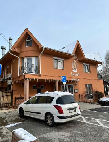 a white car parked in a parking lot in front of a building at 4 Hordó - Panzió és Étterem in Komárom