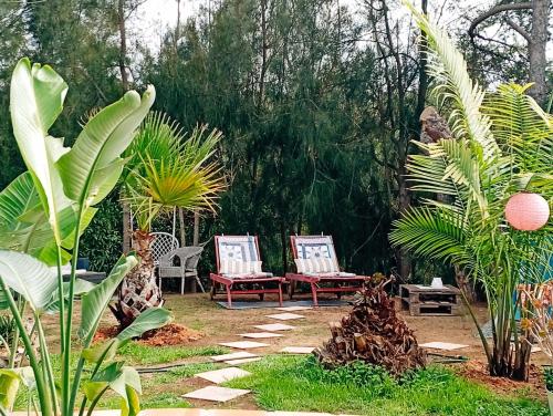 a garden with two chairs and palm trees at Bohème Valdareina, PISCINE CHAUFFEE, Bénagil-Carvoeiro in Carvoeiro