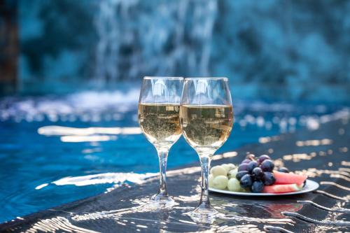 two glasses of white wine next to a plate of fruit at Naomi Boutique Suites in Netu'a
