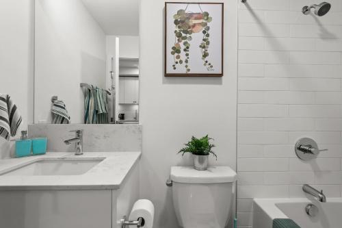 a bathroom with a sink and a toilet with a plant on it at GlobalStay Cozy 1 Bedroom Condo with Balcony Downtown Calgary in Calgary