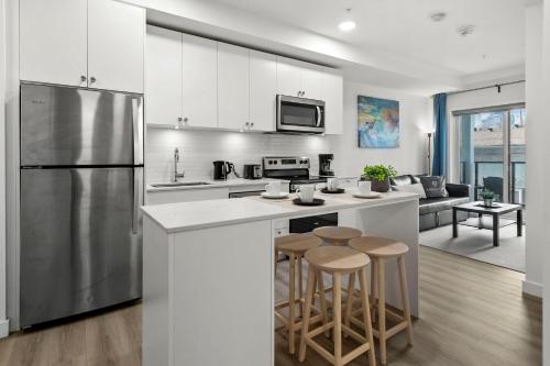 a kitchen with a stainless steel refrigerator and stools at GlobalStay Cozy 1 Bedroom Condo with Balcony Downtown Calgary in Calgary