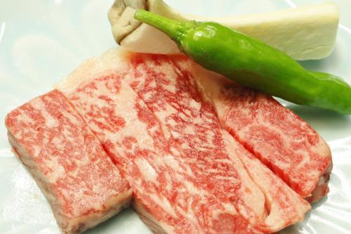 a piece of meat with a piece of cheese and a green pepper at Takasagoya Ryokan in Zao Onsen