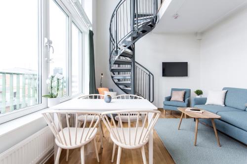 a living room with a staircase and a table and chairs at Biz Apartment Hammarby Sjöstad in Stockholm