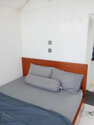 a bed with a wooden headboard and two pillows at Villa Miradarma in Sembalun Lawang