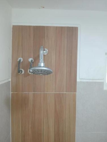 a bathroom with a shower head on a wooden door at Villa Miradarma in Sembalun Lawang