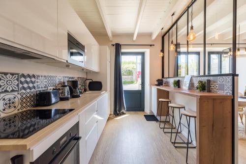 una cocina con barra y un bar con taburetes en Paradis côtier - Maison vue mer à Loguivy, en Loguivy-Plougras