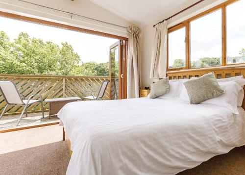 a bedroom with a large bed and a balcony at Landal Leycroft Valley in Perranzabuloe