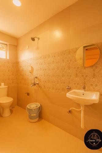 a yellow bathroom with a sink and a toilet at Hotel Amore Mio Morjim - Beachfront Hotel on Morjim Beach in Morjim