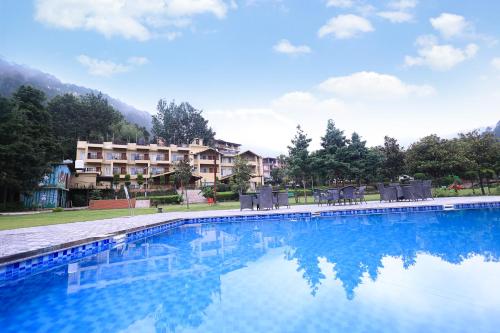 a swimming pool with chairs and a hotel in the background at Foxoso Misty Oaks - Hotel & Resort in Bhowāli