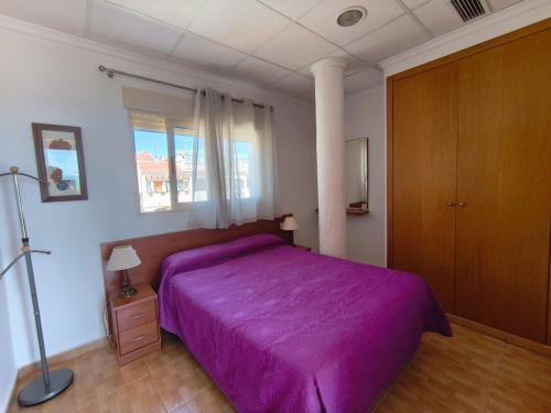 a bedroom with a purple bed and a window at Apartamentos Bellavista in Puerto de Mazarrón