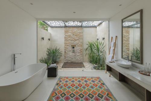a bathroom with a tub and two sinks and a shower at Chandra Bali Villas in Seminyak