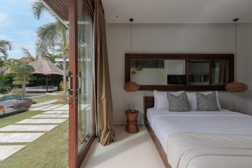 a bedroom with a bed and a view of a yard at Chandra Bali Villas in Seminyak