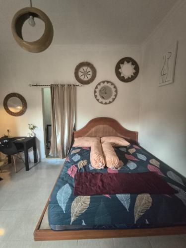 1 cama en un dormitorio con relojes en la pared en Little Loti Sikumana, en Maulafa