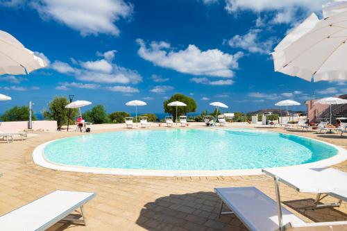 une grande piscine avec chaises longues et parasols dans l'établissement Residence Rocce Rosse, à Isola Rossa