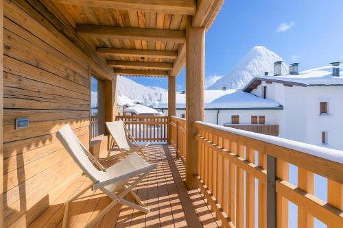 twee stoelen op een terras met bergen op de achtergrond bij Besseghini Apartments in Livigno