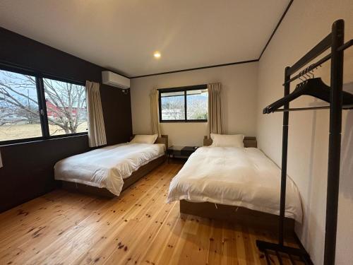 Un dormitorio con dos camas y dos ventanas. en Yukiguni Base Hakuba, en Hakuba