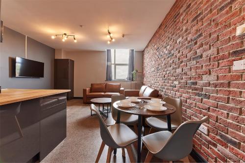 a room with a brick wall and a table and chairs at Apartment Stays in Newcastle upon Tyne