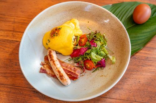 een witte plaat met eten op een houten tafel bij The Riverfront Reserve in Pai