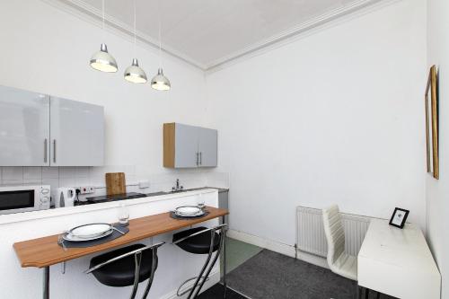 a white kitchen with a wooden table and chairs at Montague House Apartments in Llandudno