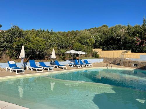 a swimming pool with lounge chairs and umbrellas at Blu Marlin Apartment in Santa Maria Coghinas