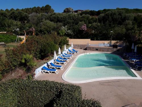 a swimming pool with lounge chairs and umbrellas at Blu Marlin Apartment in Santa Maria Coghinas