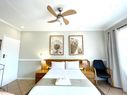 Un dormitorio con una cama y un ventilador de techo. en Clubview Guest House, en Centurion