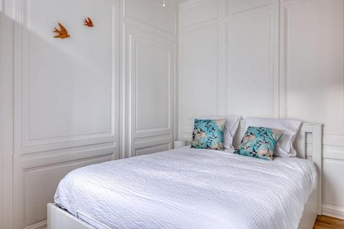 ein weißes Schlafzimmer mit einem weißen Bett und blauen Kissen in der Unterkunft Blue Bird charmant studio avec place de parking ! in Rouen