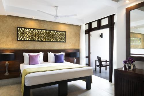 a bedroom with a bed with purple pillows at Avani Kalutara Resort in Kalutara