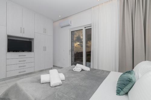 una camera da letto bianca con un letto e asciugamani di Villa Orizzonte- First Floor Apartment a Città di Zante