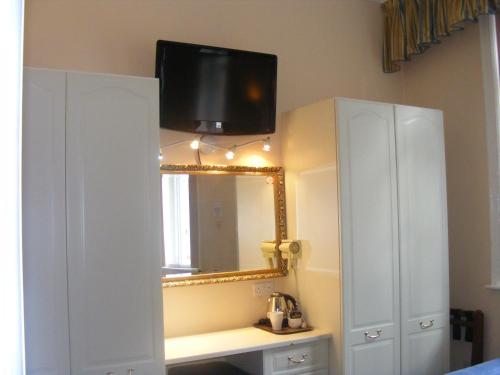 baño con espejo y TV en la pared en Mermaid Suite Hotel, en Londres