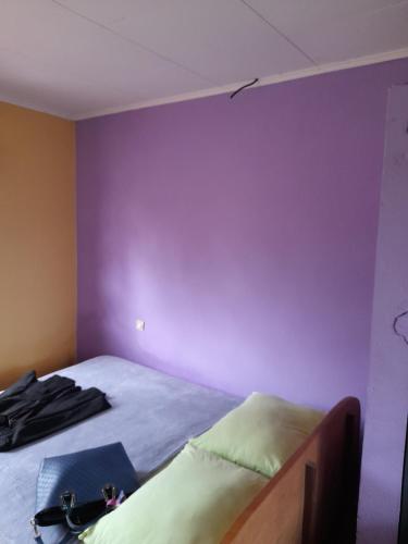 een slaapkamer met een paarse muur en een bed bij La casa in Kribi