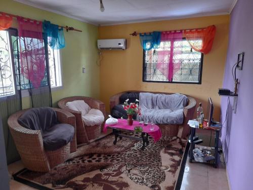 een woonkamer met rieten stoelen en een tafel bij La casa in Kribi