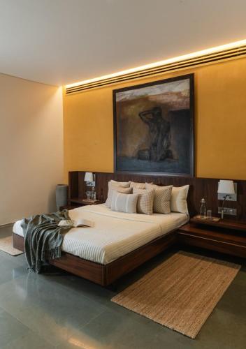 a bedroom with a large bed with a painting on the wall at LohonoStays Villa Gomti in Lonavala