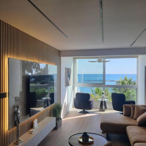a living room with a couch and a large window at Amato Beach in Limassol