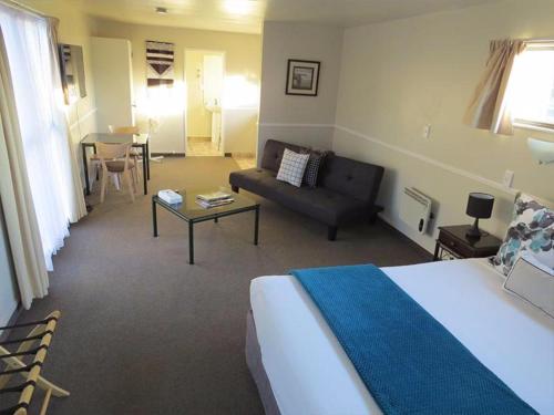 a bedroom with a bed and a couch and a table at Pohutu Lodge Motel in Rotorua