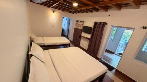 ein Zimmer mit 2 Betten und einem Fenster in der Unterkunft Wildcrest Homestay in Madikeri