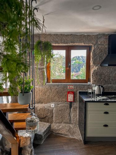 a stone kitchen with a sink and a window at Casa do Cabeço de Boi by Refúgio ao Luar in Terras de Bouro